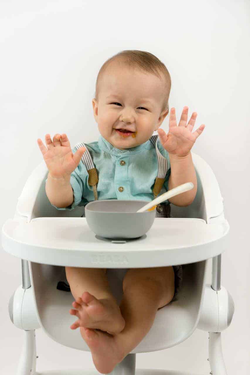 Toddler Smiling in High Chair with Meal Set in Use
