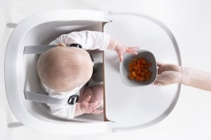 Overhead photo of baby reaching for berries in silicone suction bowl cloud