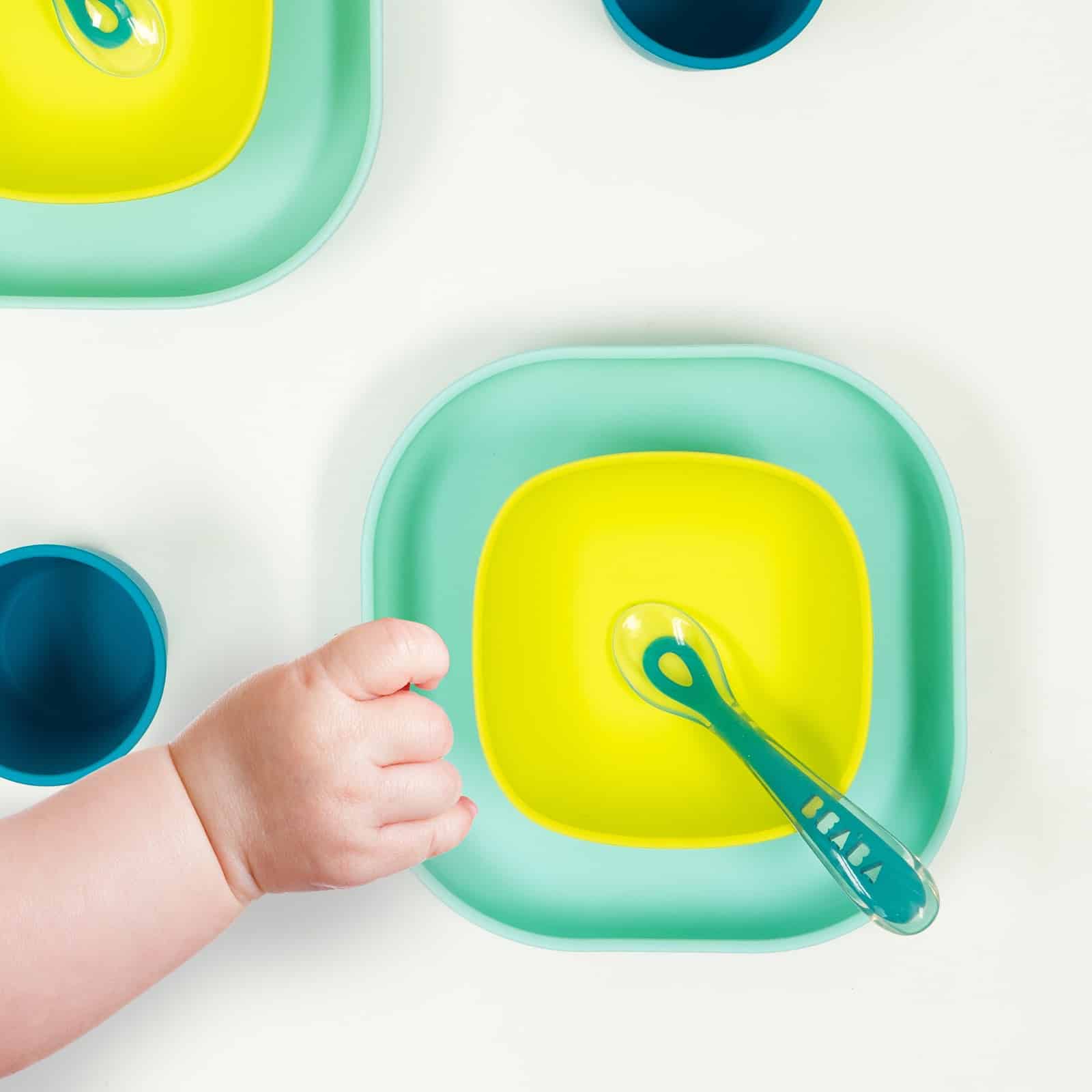 Baby hand reaching for silicone suciton meal set peacock