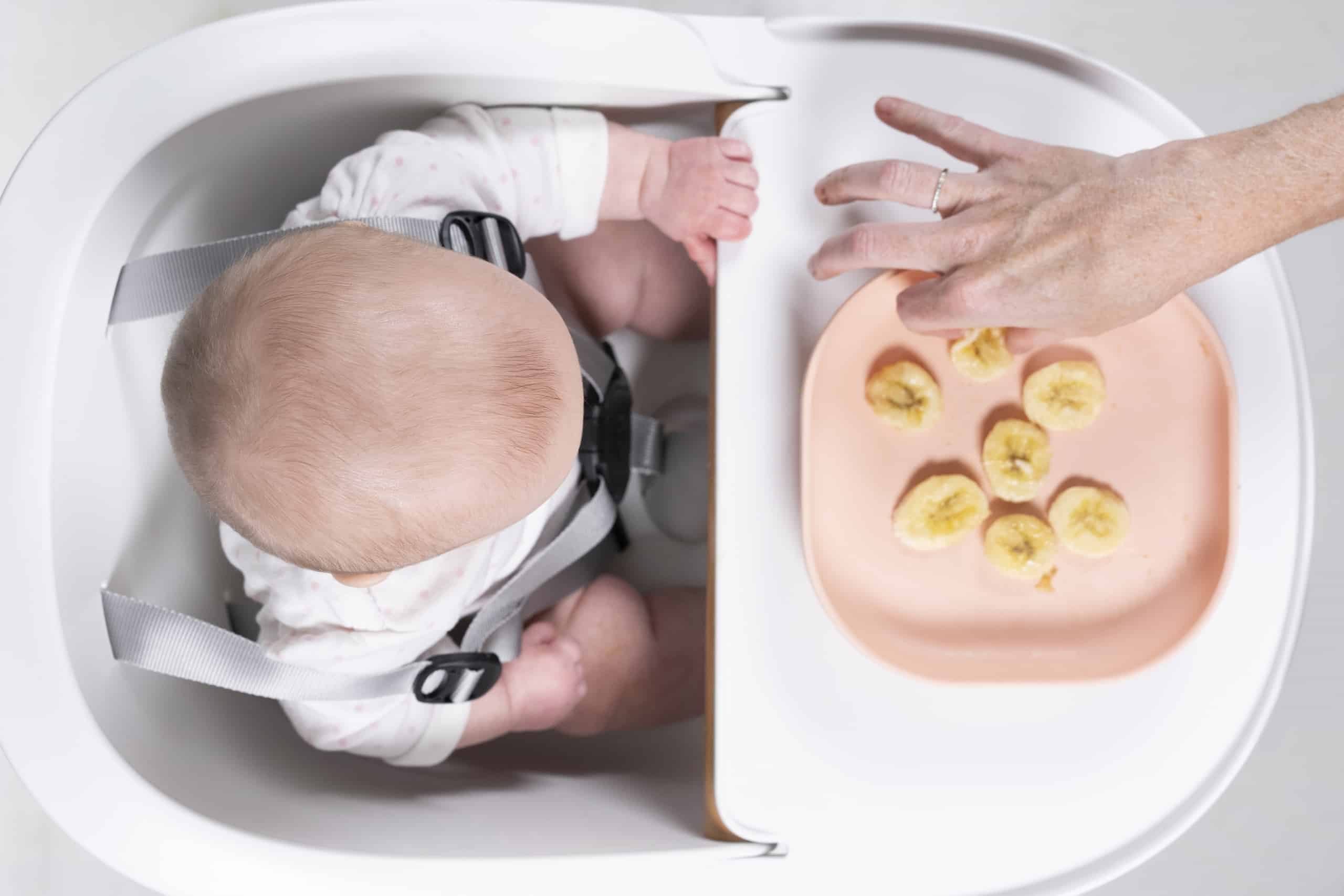 Mom feeding baby bananas from silicone suction plate rose