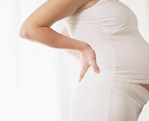 Side view woman's pregnant belly with white stretch shirt and pants