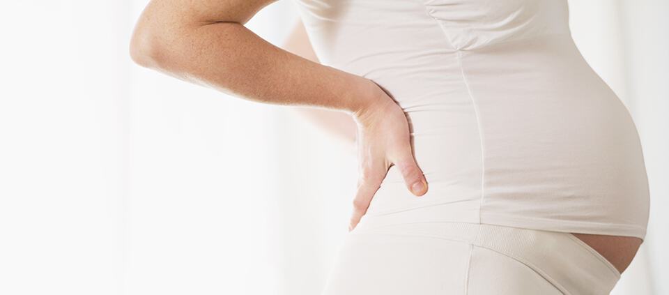 Side view woman's pregnant belly with white stretch shirt and pants