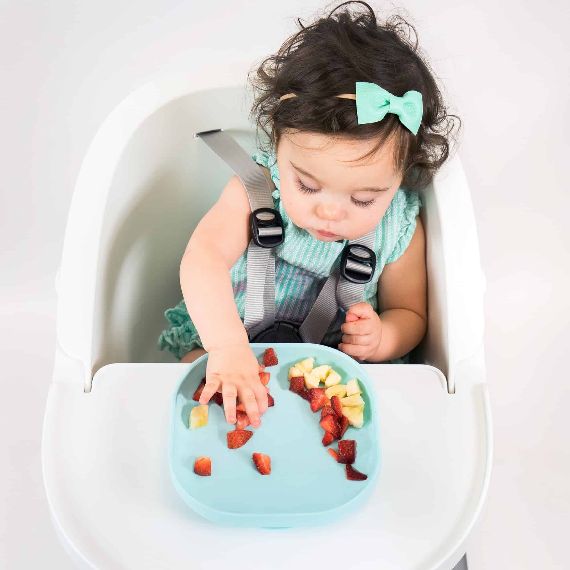 Toddler picking fruit from silicone suction meal set pastel