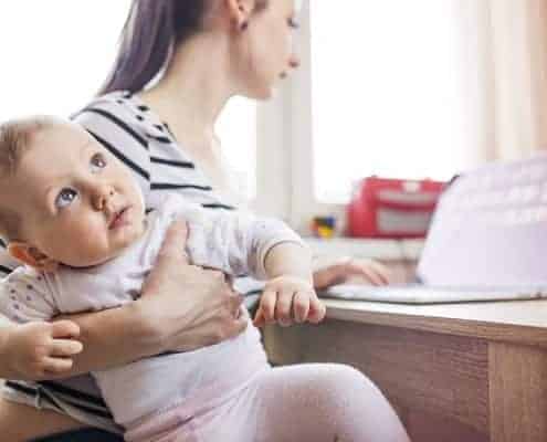 Mom Working on Laptop While Holding Baby