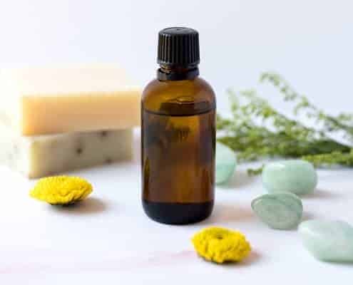Essential oil in bottle next to soap and herbs