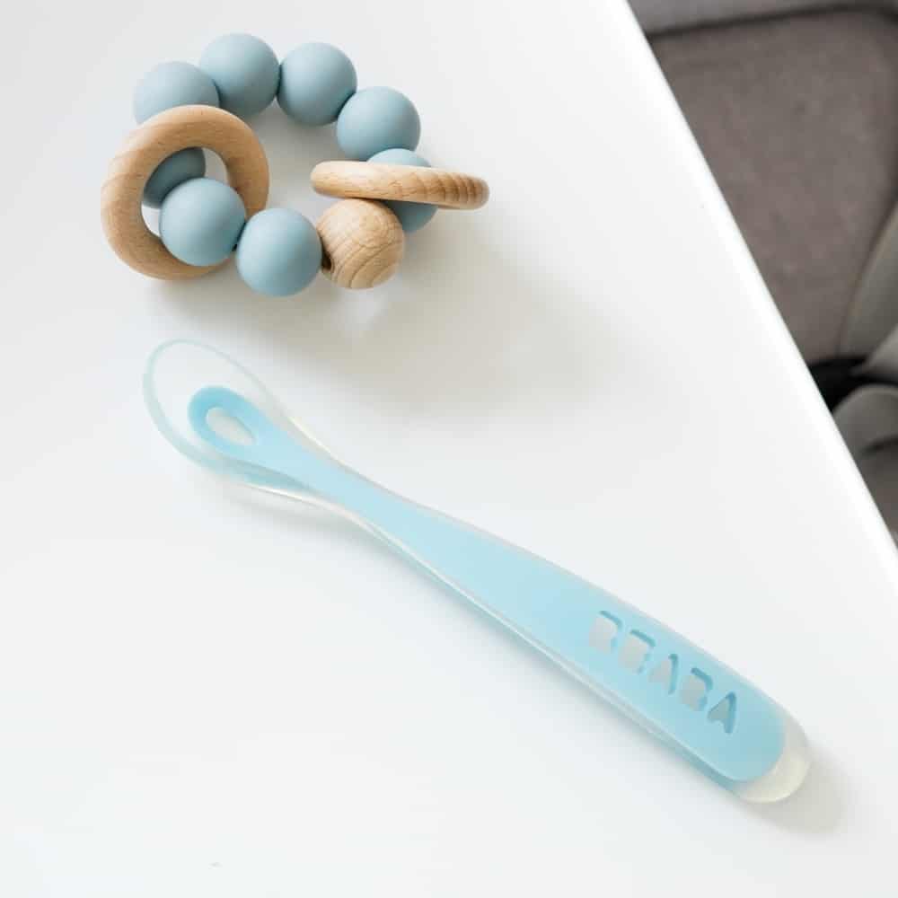 Beaba first foods spoon on high chair tray next to rattle