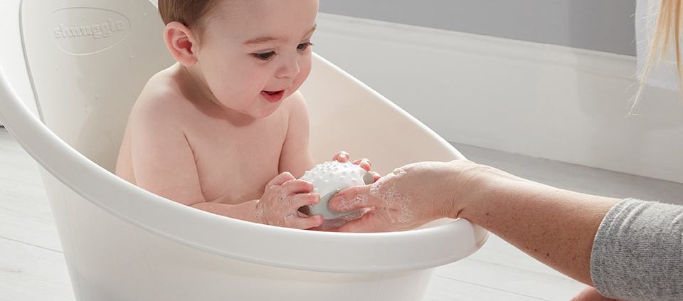 Baby playing in Beaba by Shnuggle Baby bath in grey