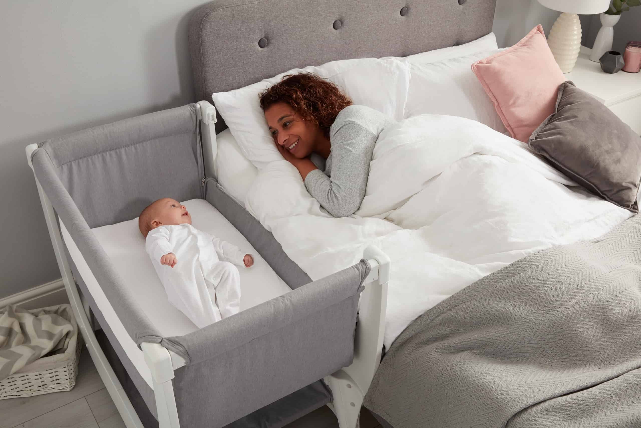 Mom Looking At Baby In Beaba by Shnuggle Air Bedside Sleeper Infant Crib
