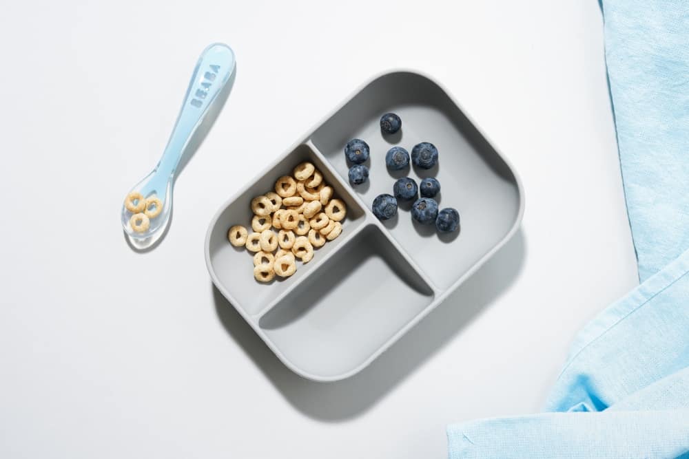 Beaba Divided Suction Plate and spoon with cheerios and blueberry in it.