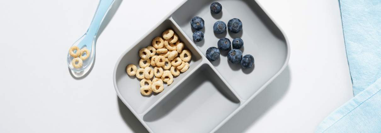 Beaba Divided Suction Plate and spoon with cheerios and blueberry in it.
