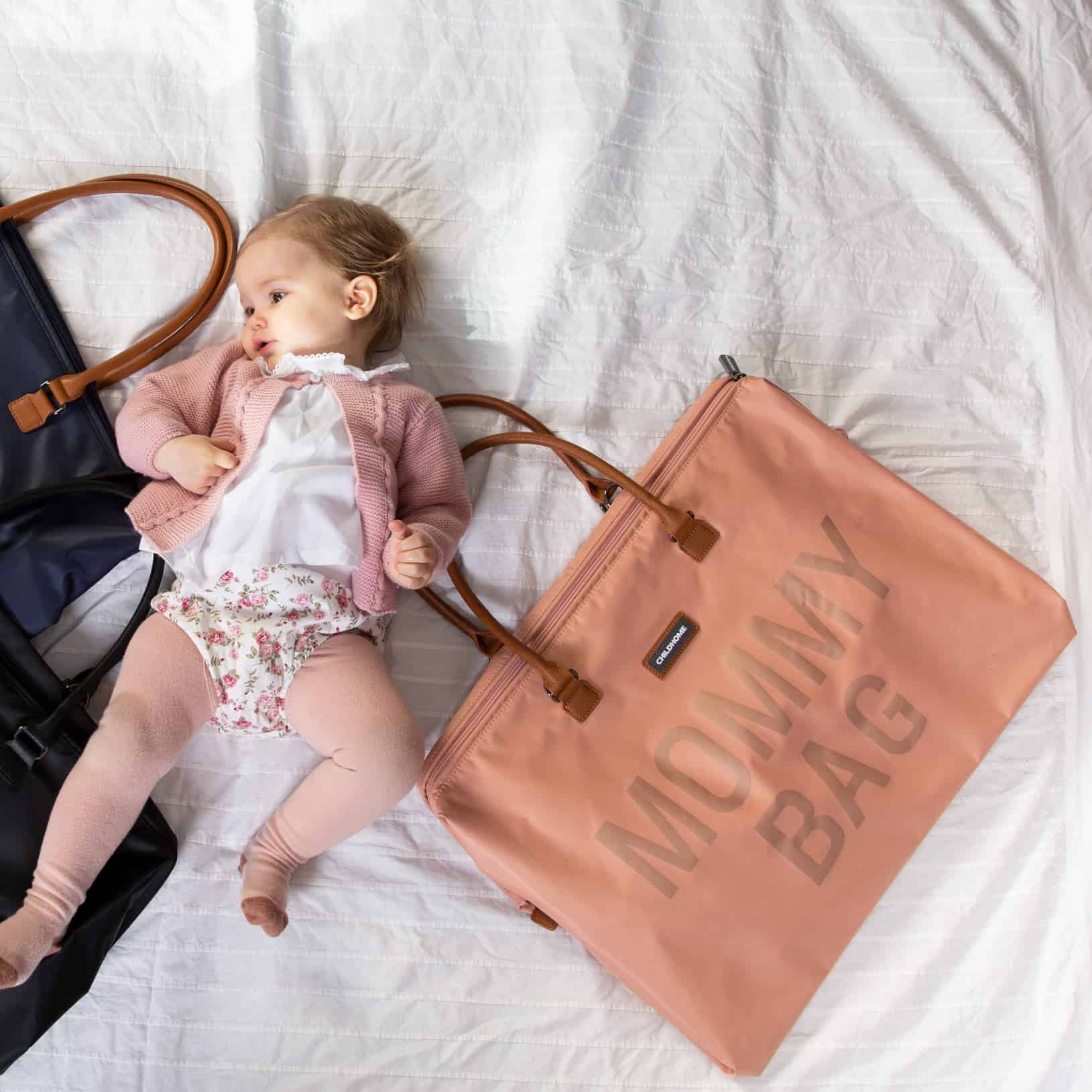 Baby laying on bed with Childhome Mommy Bag Pink/Copper