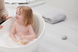 Girl in Toddler Bath with Pebbly by Floor