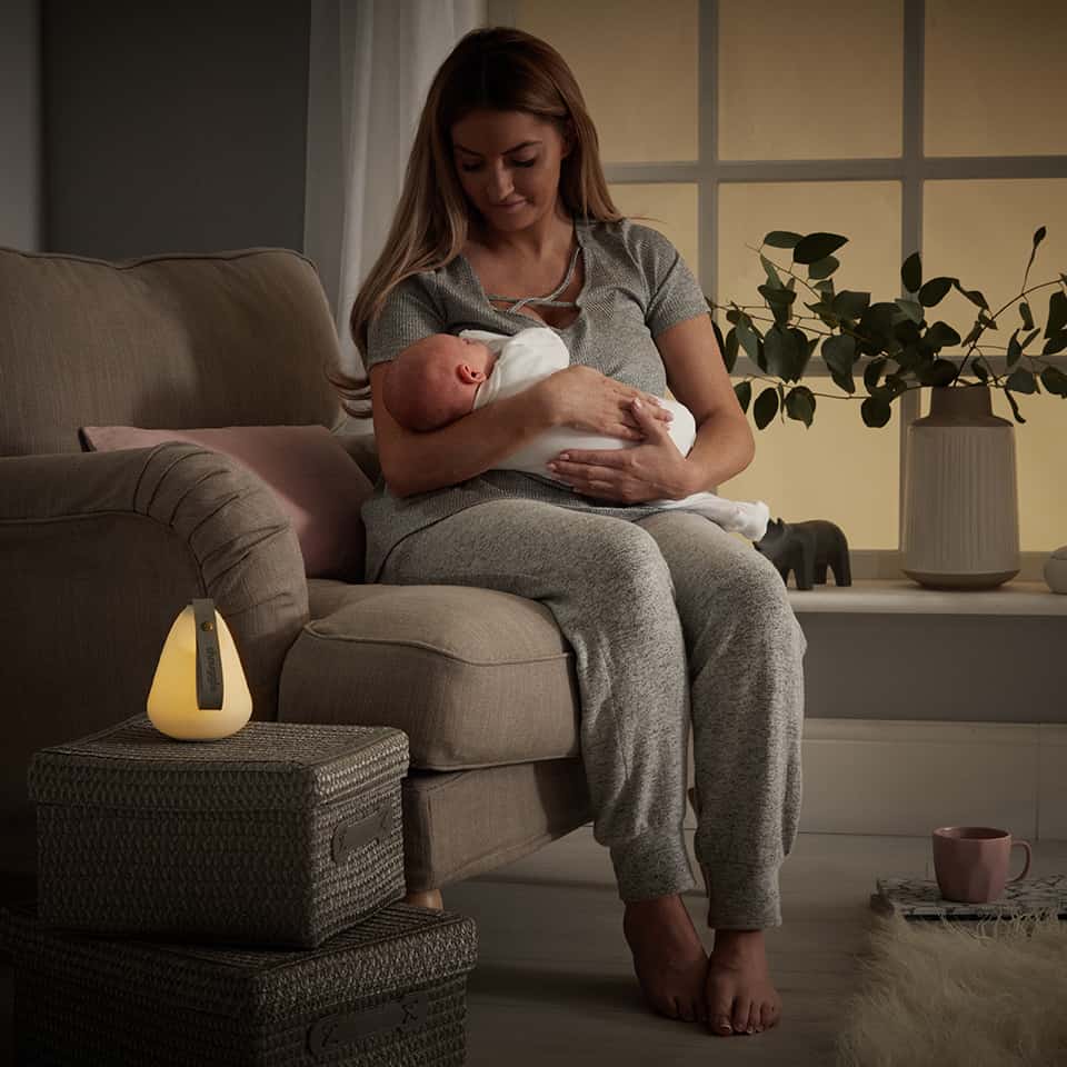Mom holding newborn next to Shnuggle Nightlight