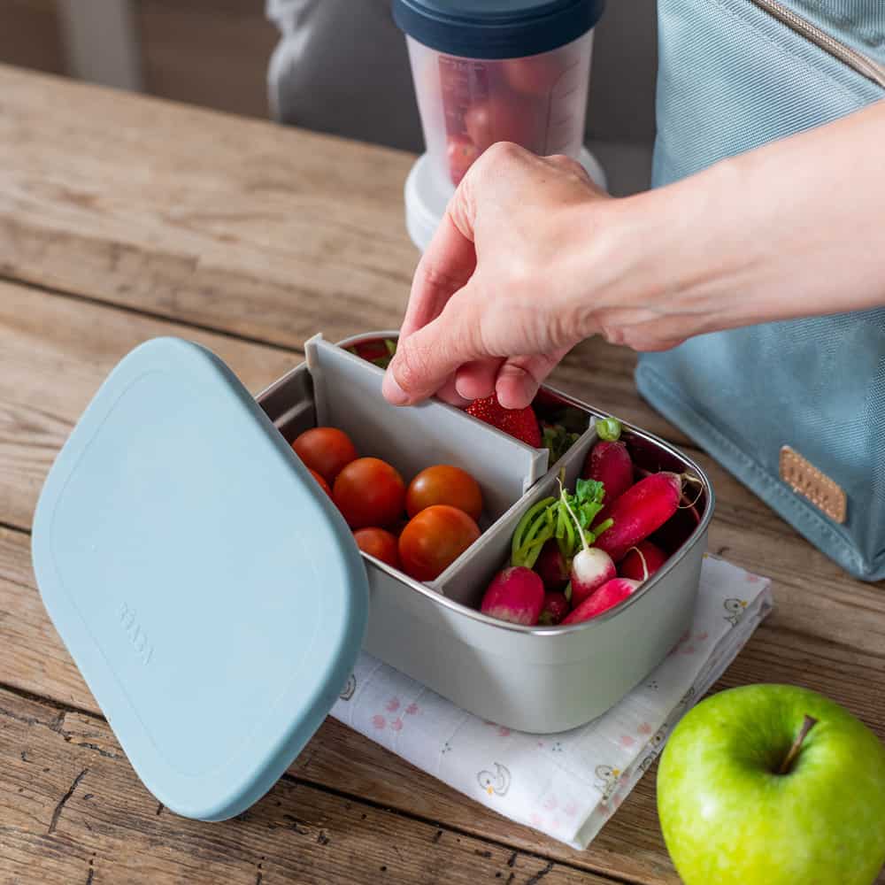 stainless steel lunch box rain with three compartments filled with red fruit