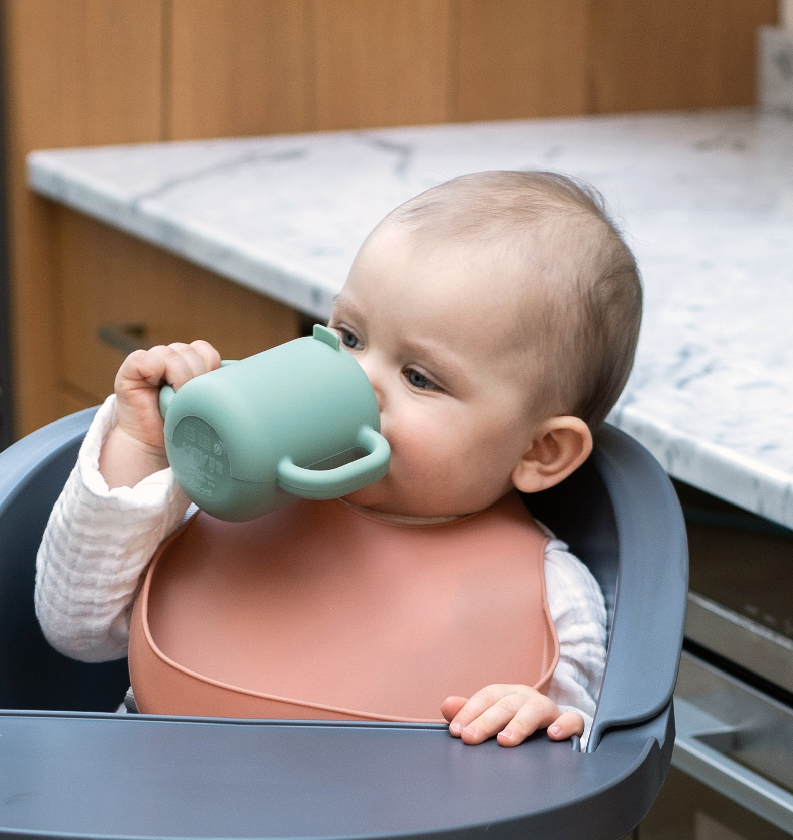 baby drinking from silicone training cup in sage