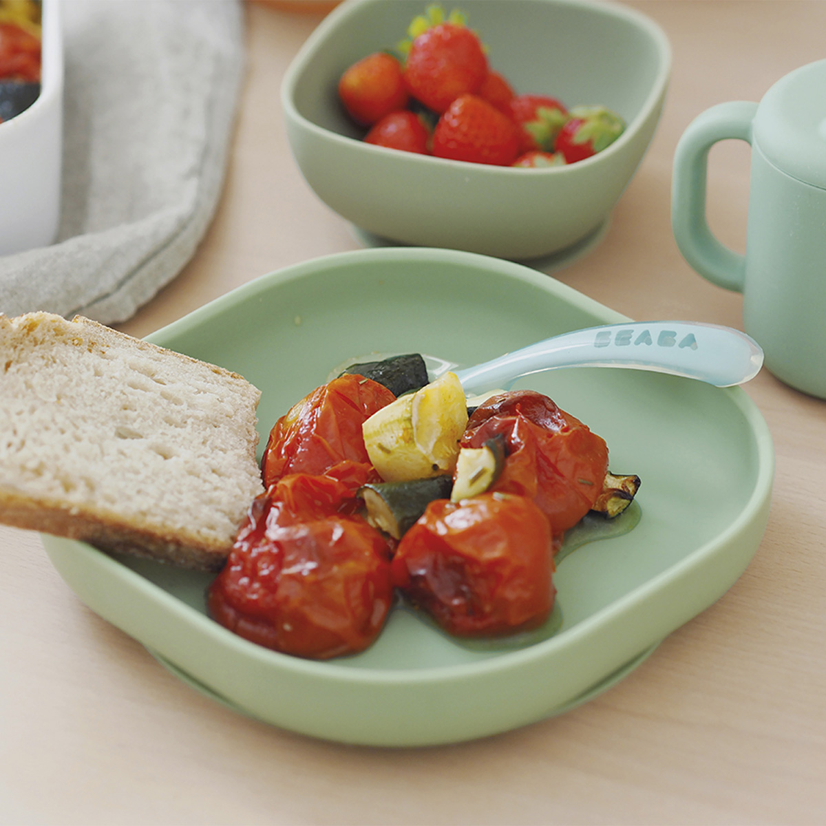 silicone suction plate sage green on kitchen table with tomatoes and toast